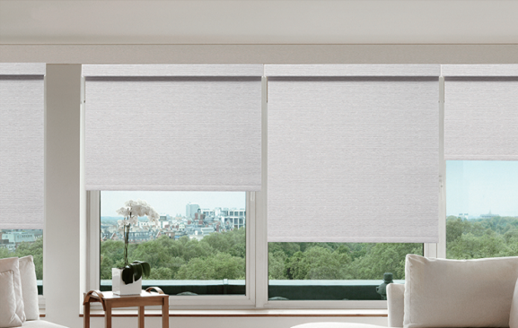 Modern living room with large windows and white roller blinds.