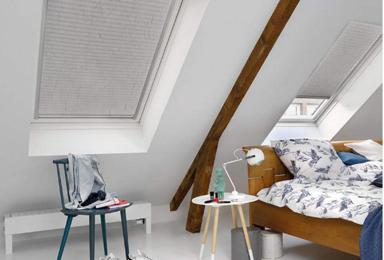 Cozy attic bedroom with a wooden bed, patterned bedding, and a small side table.